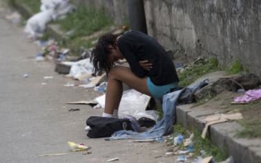 A crack addict woman sits by herself on the sidewalk , next to Parque Uniao slum during a social workers and police joint operation to take addicts out of the streets, in Rio de Janeiro, Brazil on October 26, 2012. AFP PHOTO/Christophe Simon (Photo credit should read CHRISTOPHE SIMON/AFP/Getty Images)